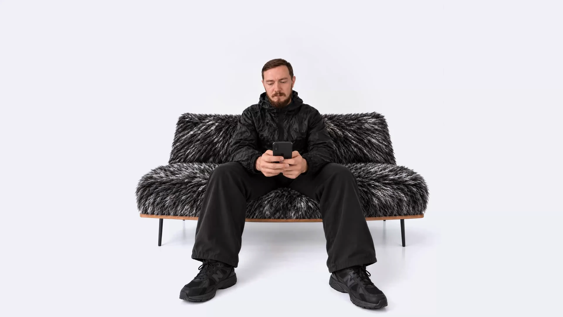 Aleksei Kipin sitting on a textured sofa, looking at his phone.
